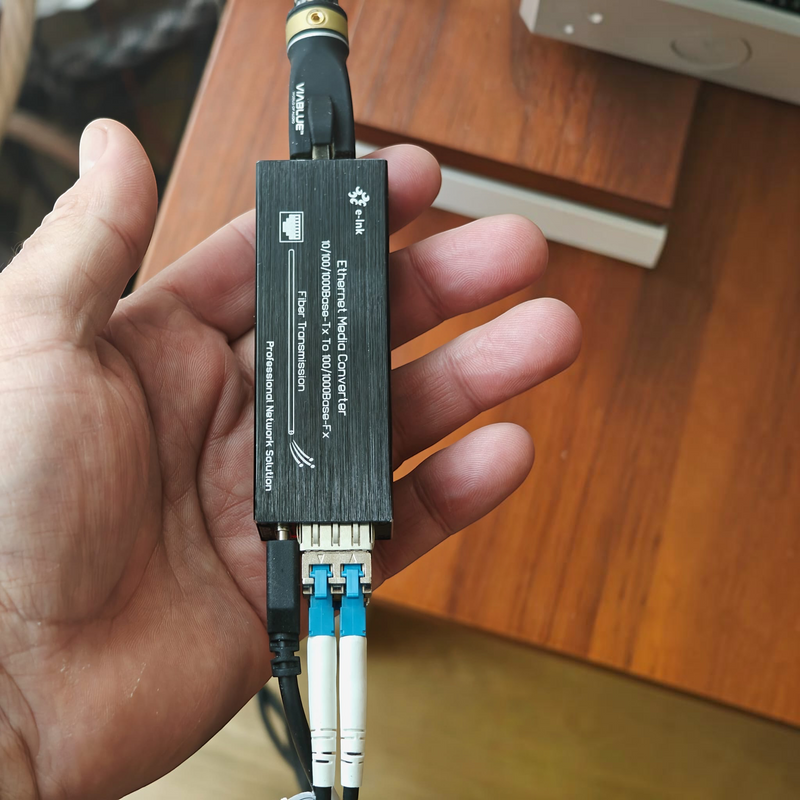 Undentia AB micro media converter held in hand, showing compact black design with SFP module and network cables
