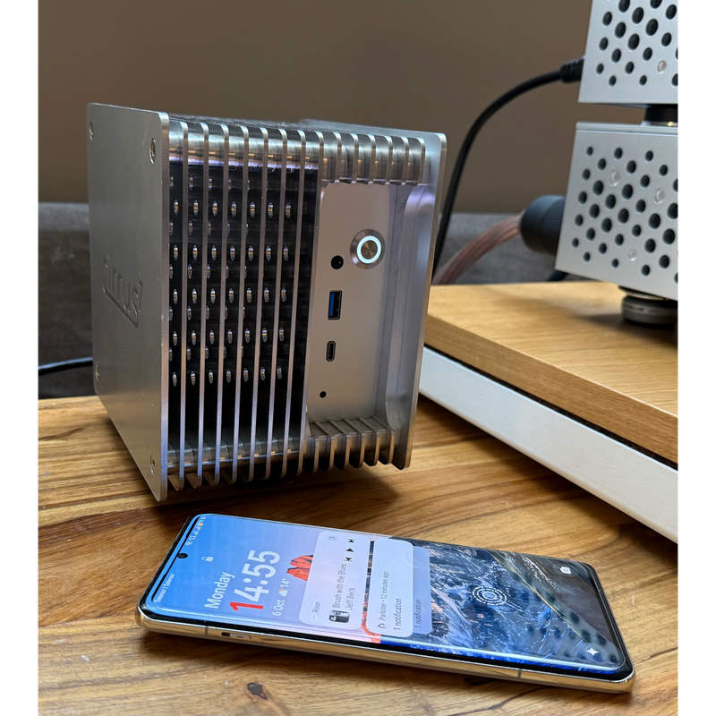 Undentia AB Cirrus7 SE silver passive-cooled music server with finned aluminum chassis next to a smartphone.